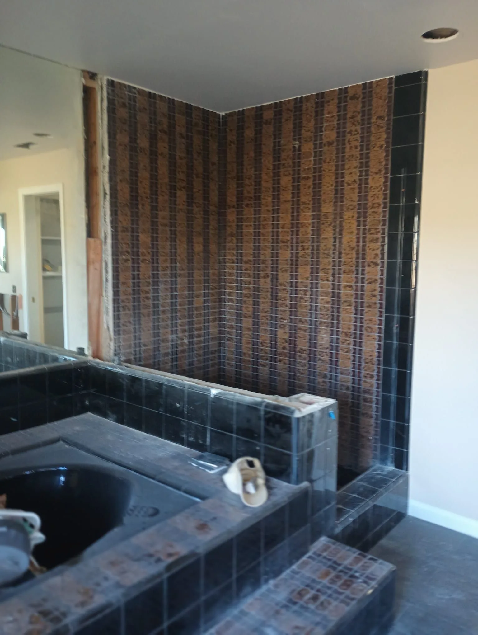 Dark tile bathroom surround during demolition