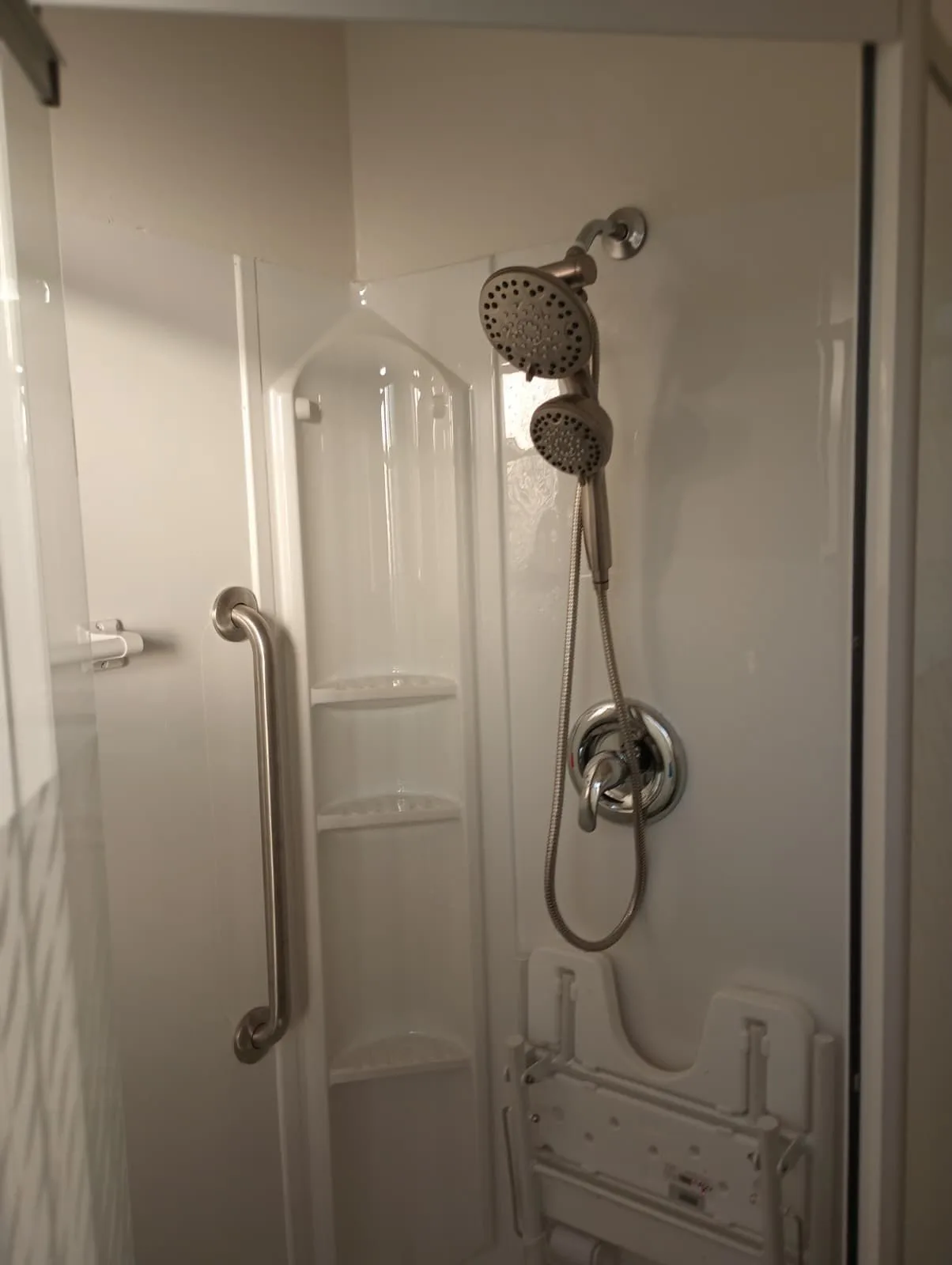 Completed accessible walk-in shower with a grab bar and fold-down seat