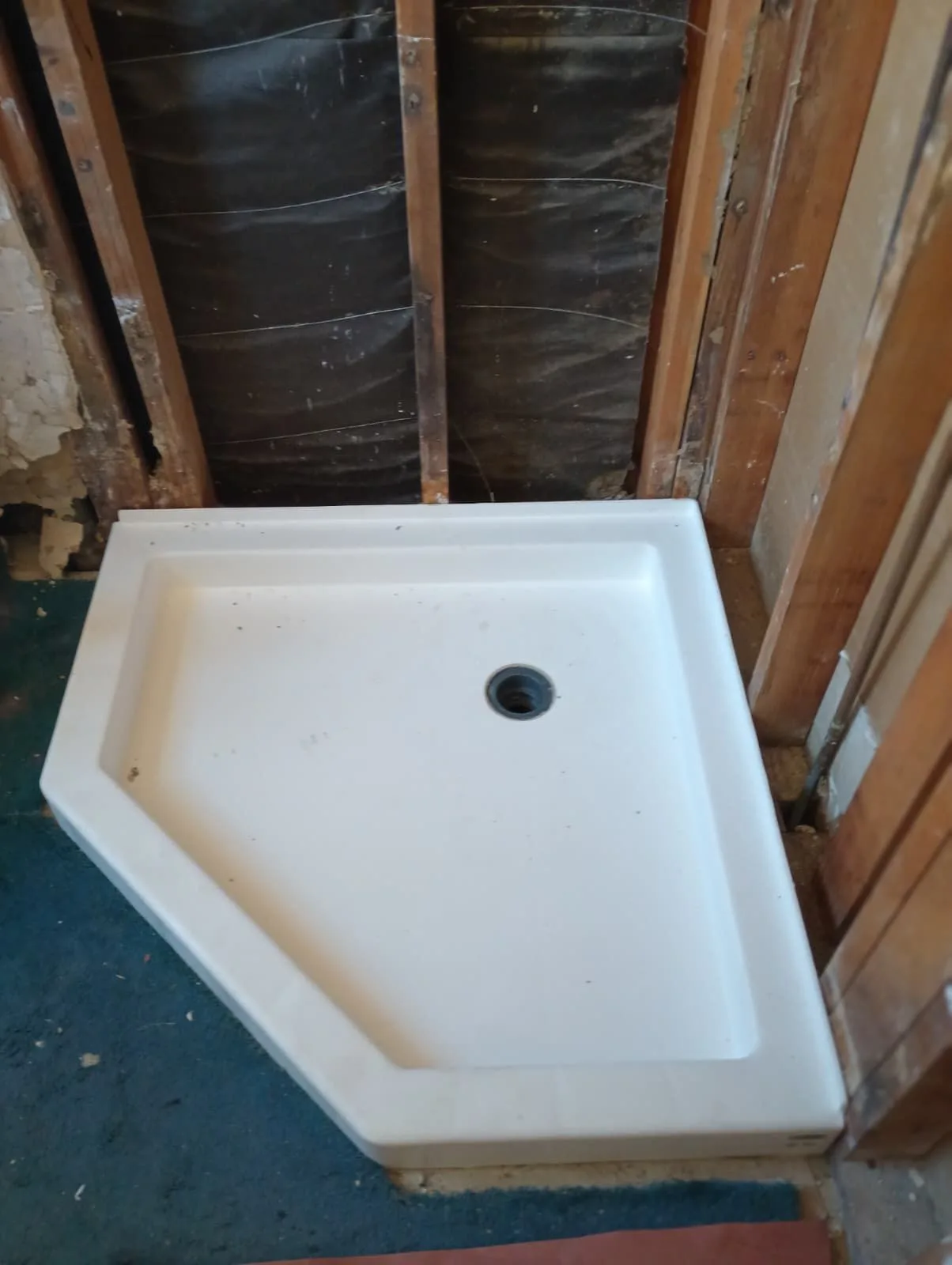 Neo-angle shower base set in a stud-framed alcove during the rough-in phase
